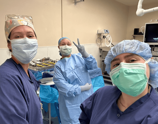 A group of nursing students in scrubs and masks in an operating room Reply