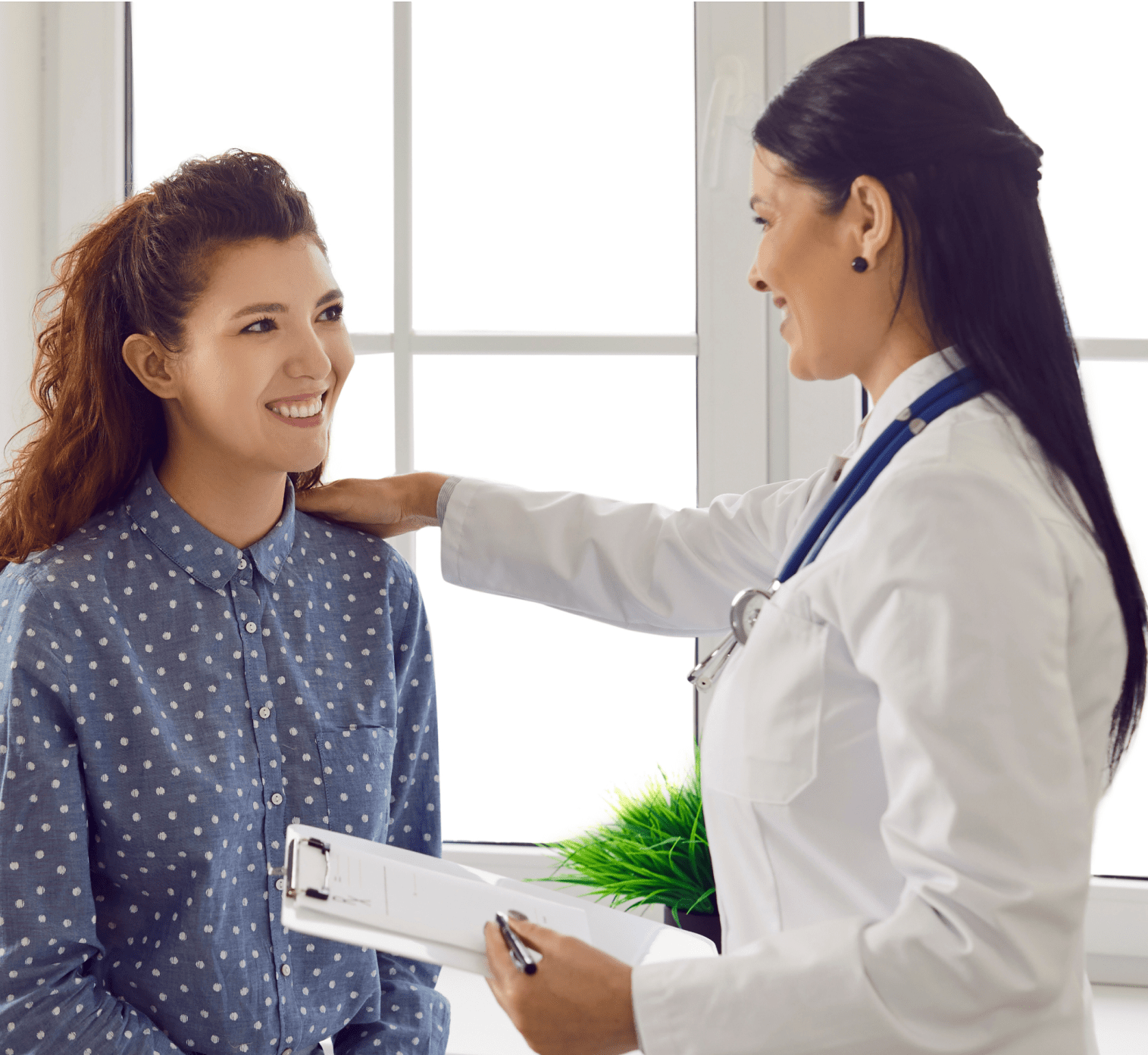 A smiling female clinician putting her hand on the shoulder of a smiling female patient