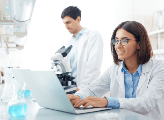 Smiling laboratory professional working at a laptop in a laboratory setting