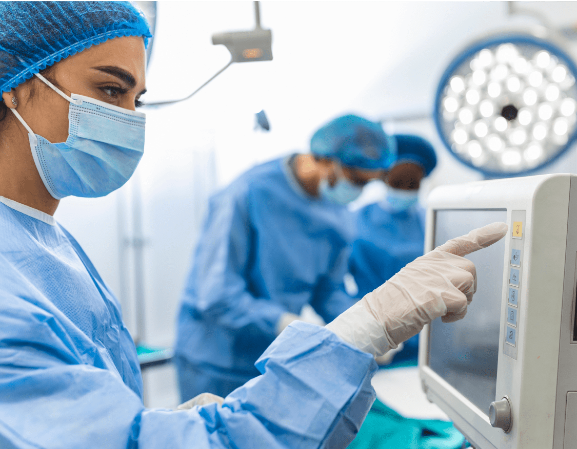 A female nurse checking patient monitoring equipment in an operating room