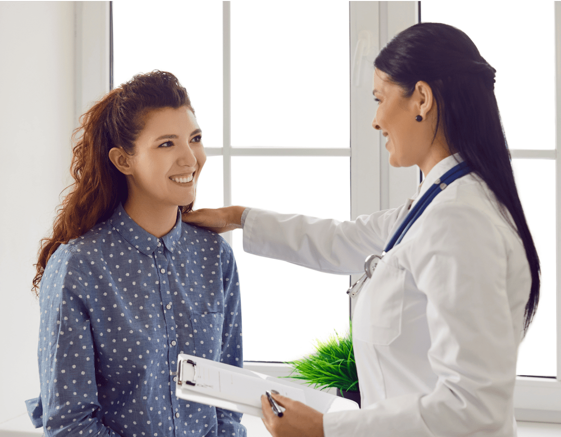 A smiling female clinician putting her hand on the shoulder of a smiling female patient