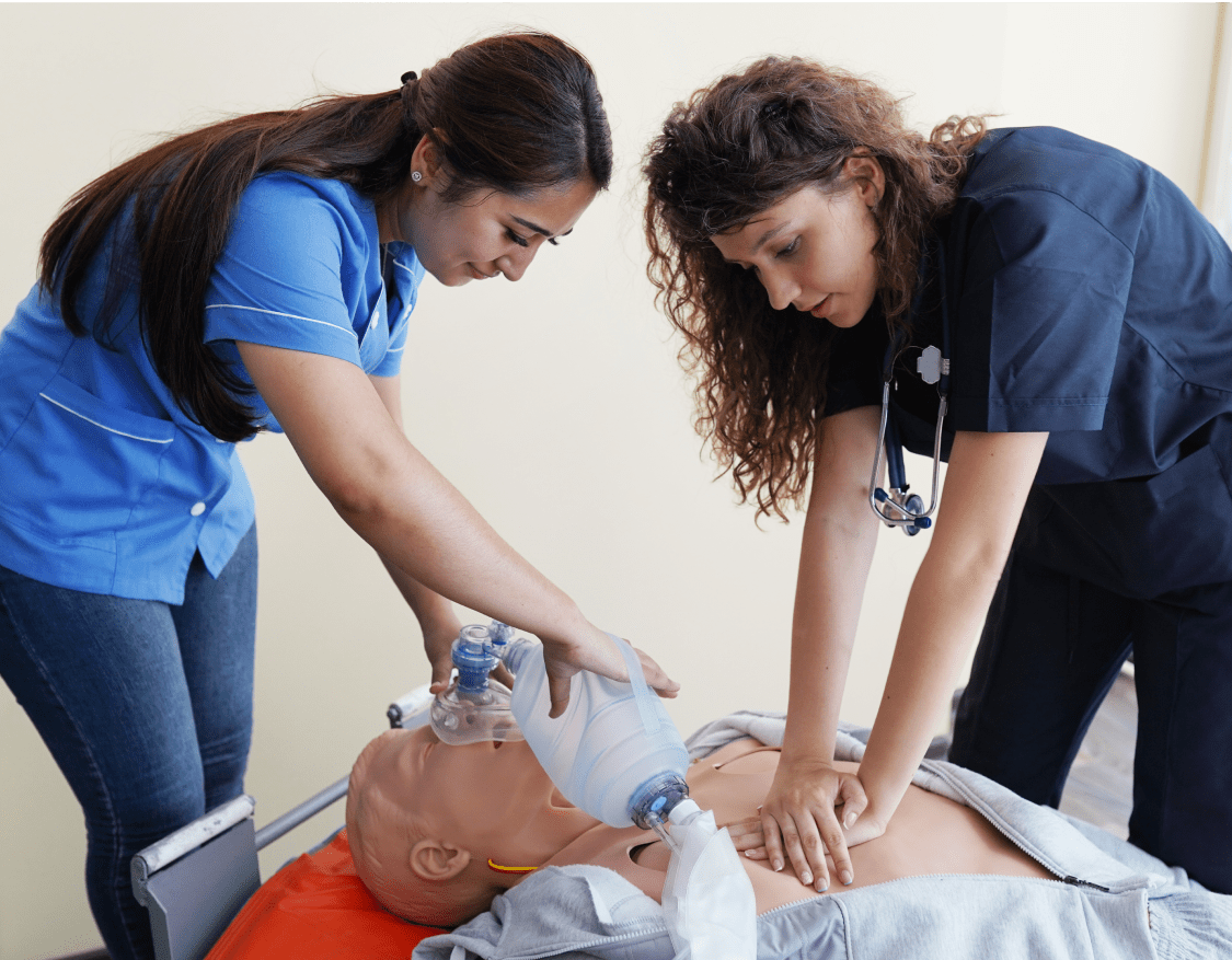 Two female nursing students practicing CPR on a CPR dummy