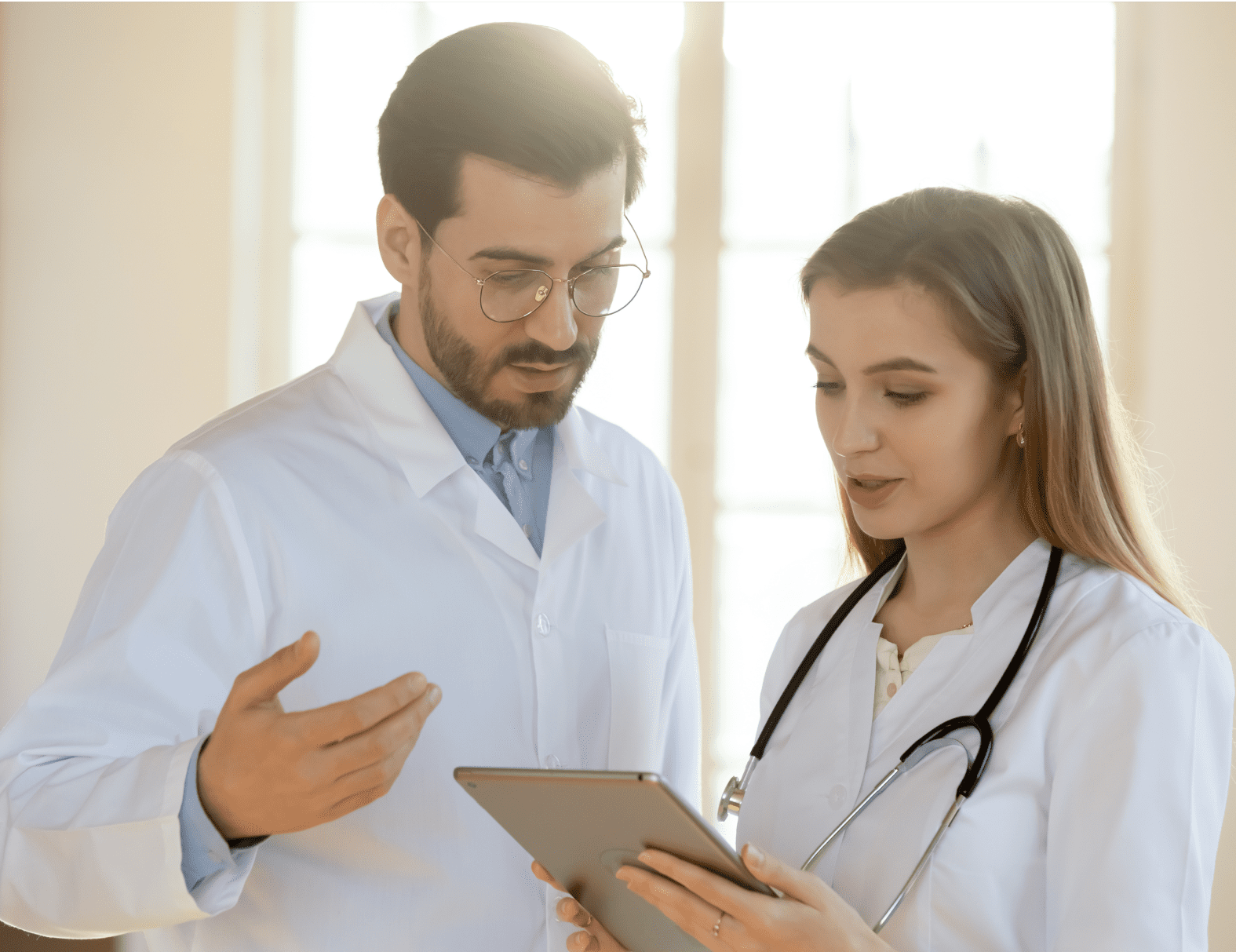 A male physician and a female nursing student collaborating on a computer tablet