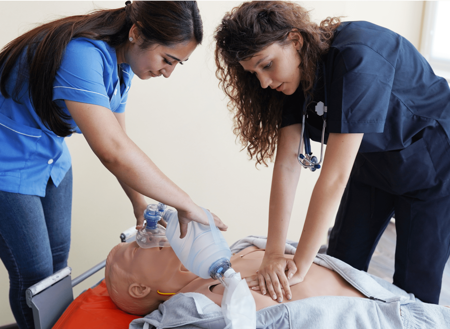 Two female nursing students practicing CPR on a CPR dummy