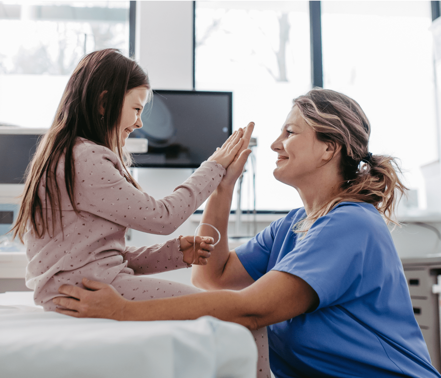 A female nurse giving a high five to a young female pediatric patient