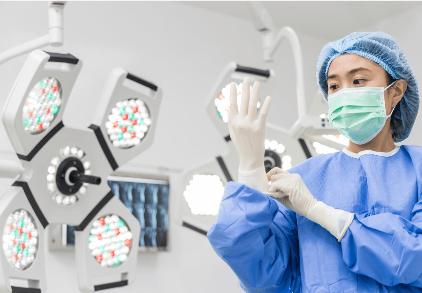 A nurse putting on surgical gloves in an operating room