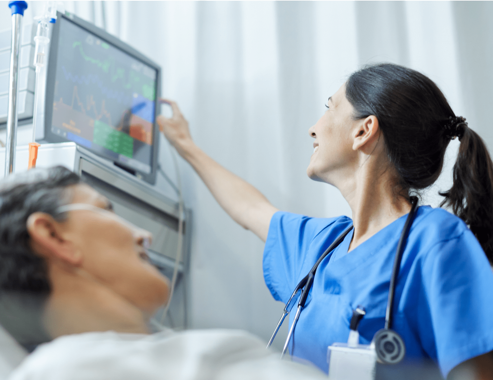 A female nurse checking monitoring equipment in a patient room