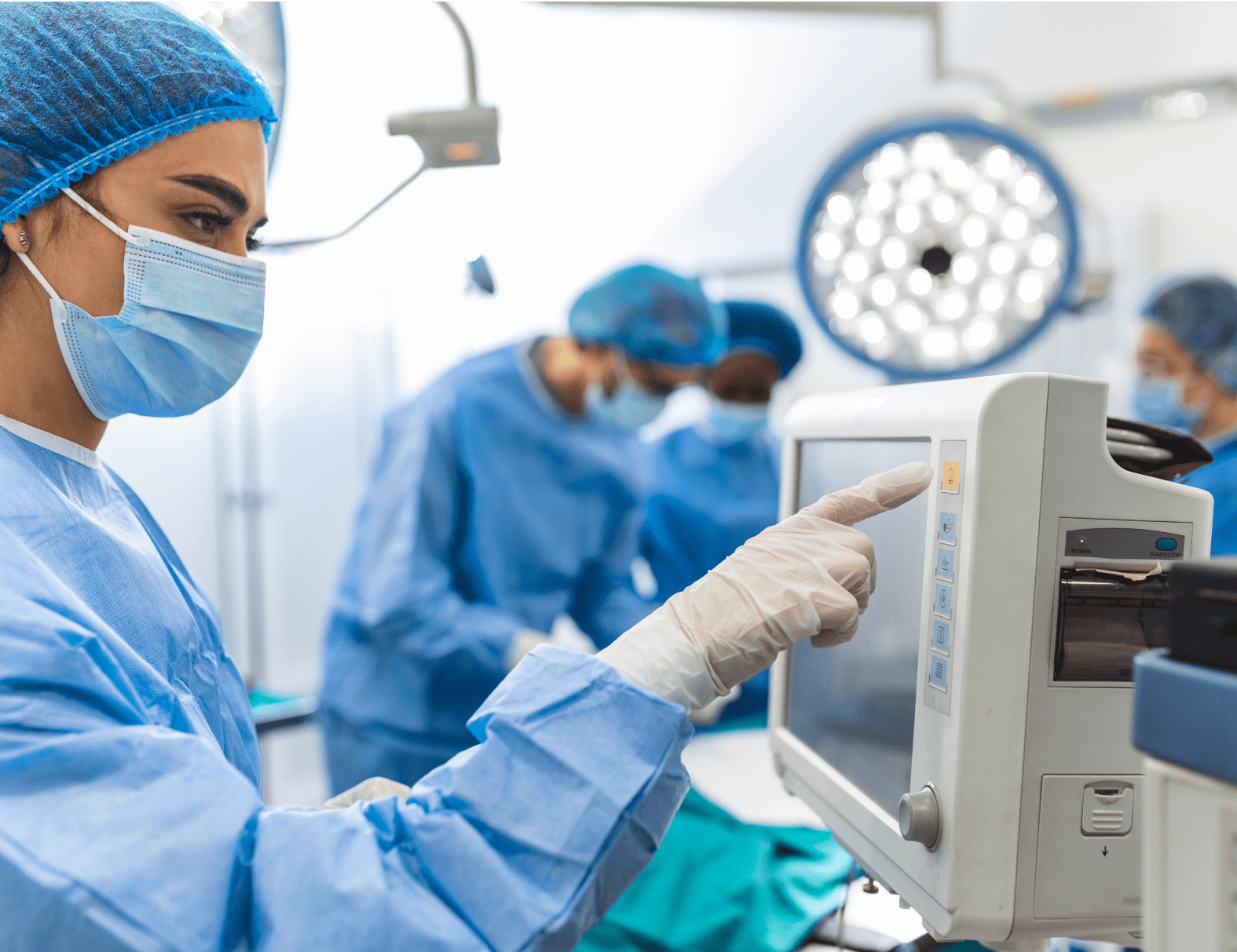 A female nurse checking patient monitoring equipment in an operating room
