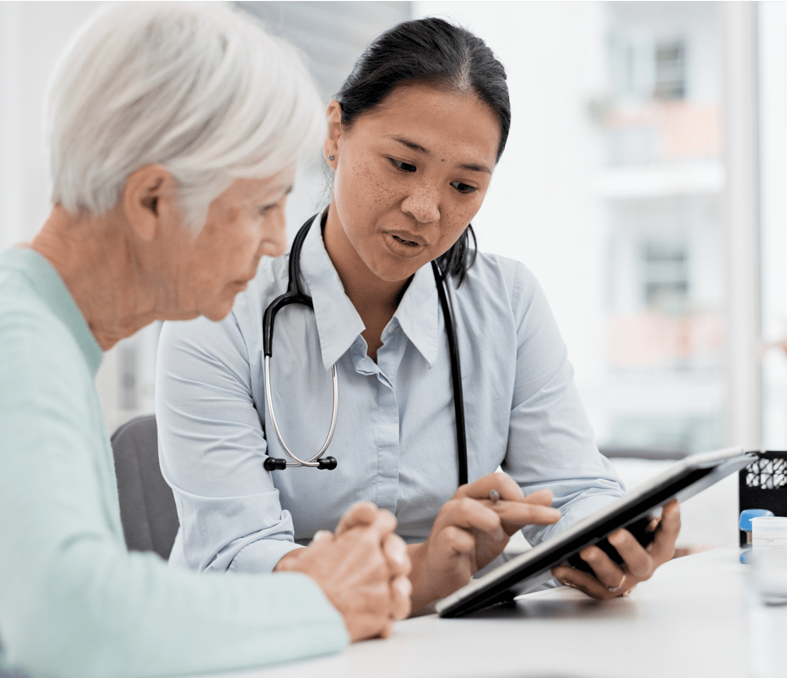 Rectangle 116 A female clinician showing an elderly female patient her chart on a computer tablet