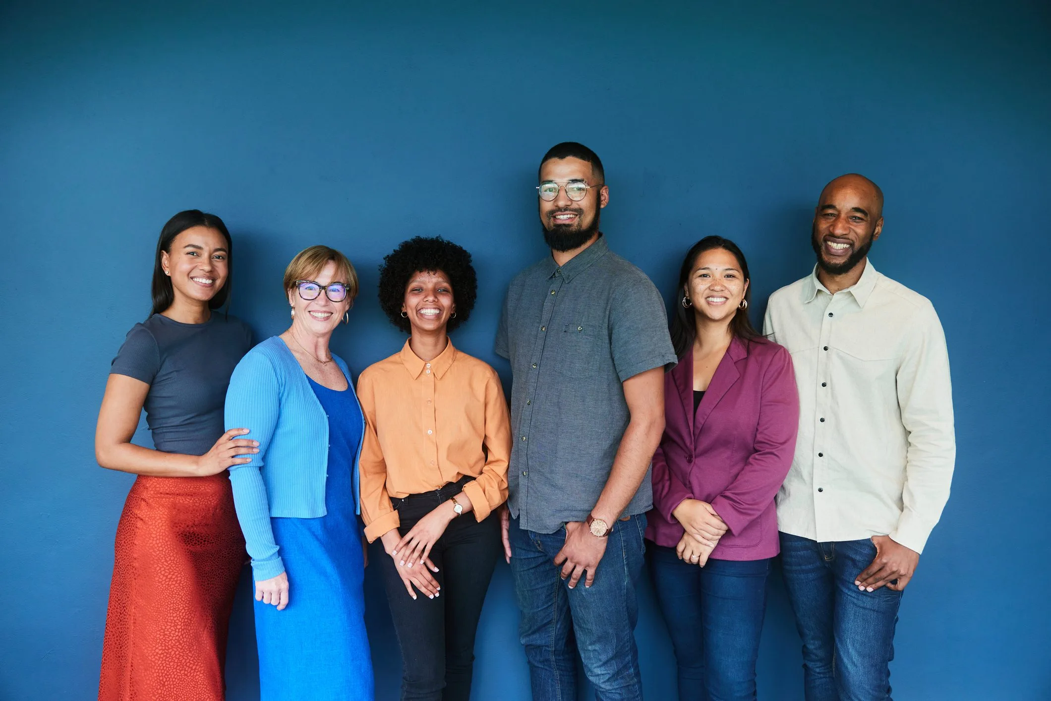 Portrait of a diverse group of smiling businesspeople standing together in front of a blue background